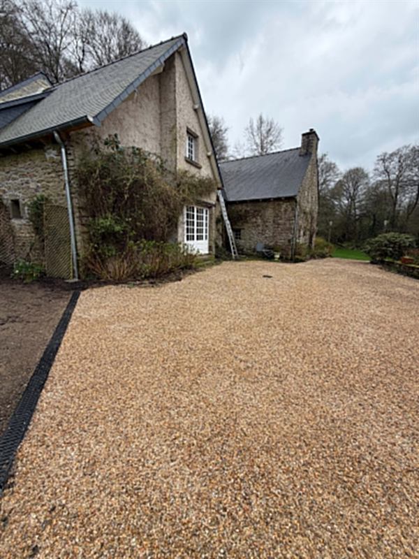 Cour en gravillon terminée devant une longère en pierre