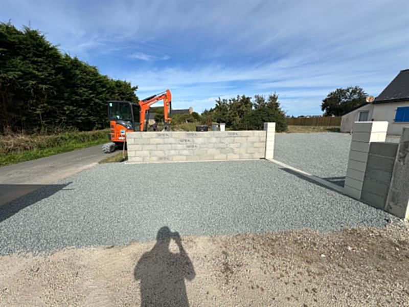 Cour en gravillon et muret d'entrée en blocs, mini-pelle sur le chantier