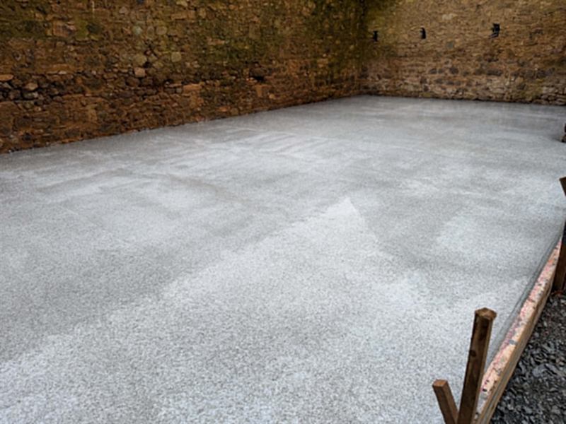 Dalle béton talochée à l'intérieur d'un bâtiment aux murs de pierre