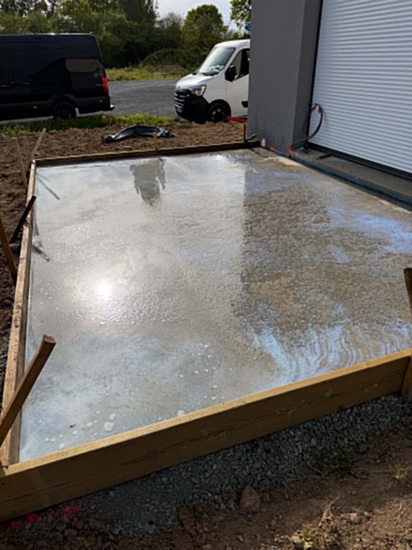 Petite dalle béton fraîchement coulée, maintenue par un coffrage bois