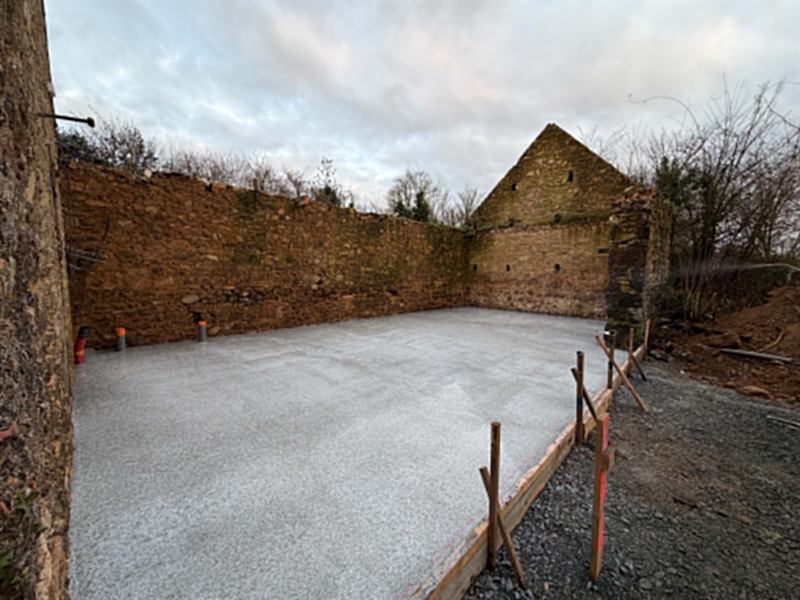 Dalle béton coulée dans une ruine en pierre, coffrage et attentes de réseaux en place