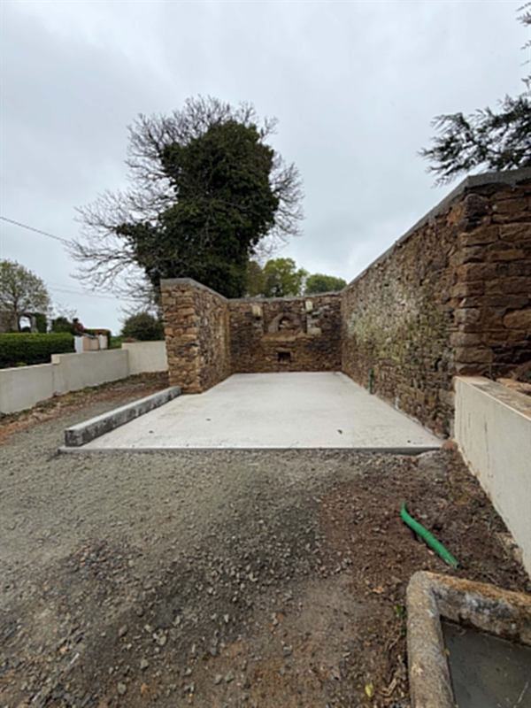 Dalle béton coulée entre des murs de pierre existants