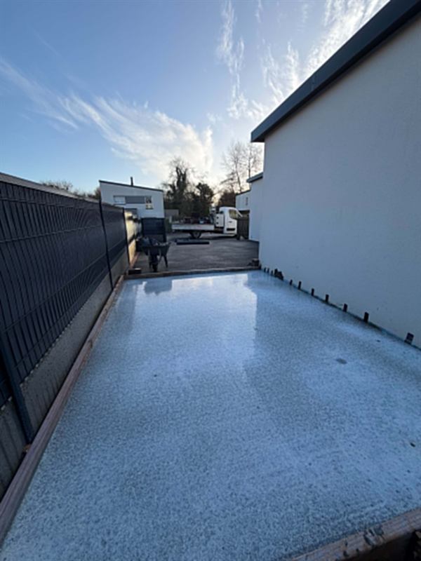 Terrasse béton coulée le long d'une maison, en limite de clôture