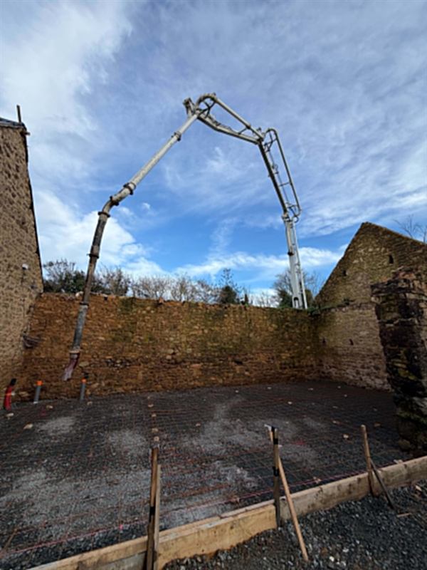 Coulage au camion pompe sur treillis soudé, à l'intérieur de murs en pierre