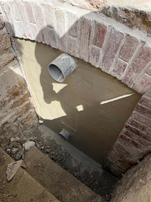 Regard maçonné et enduit sous un linteau de brique, avec attentes de canalisation