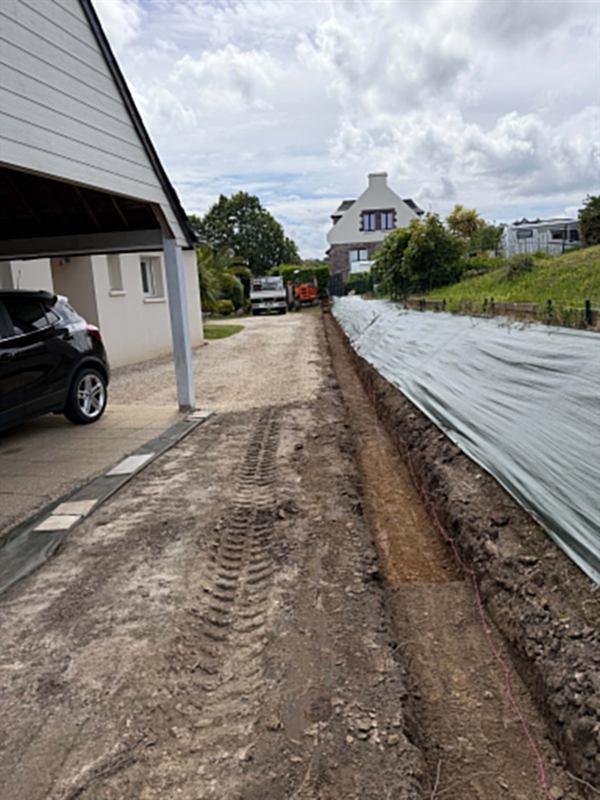 Tranchée de réseaux ouverte le long d'une maison, talus protégé par un géotextile