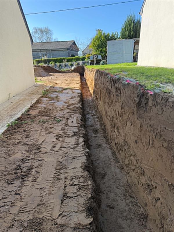 Tranchée profonde creusée dans le passage étroit séparant deux maisons