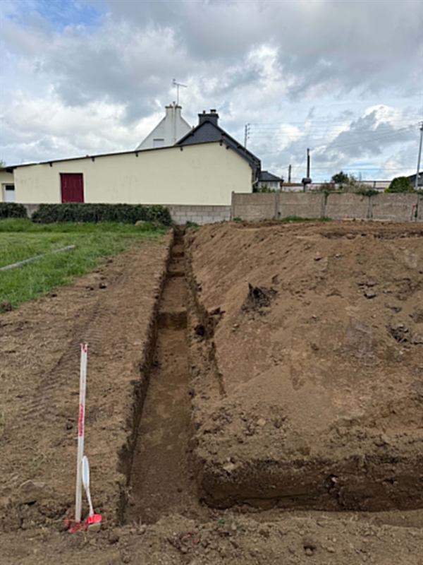 Tranchée étroite en bordure d'une plateforme décaissée, devant un bâtiment