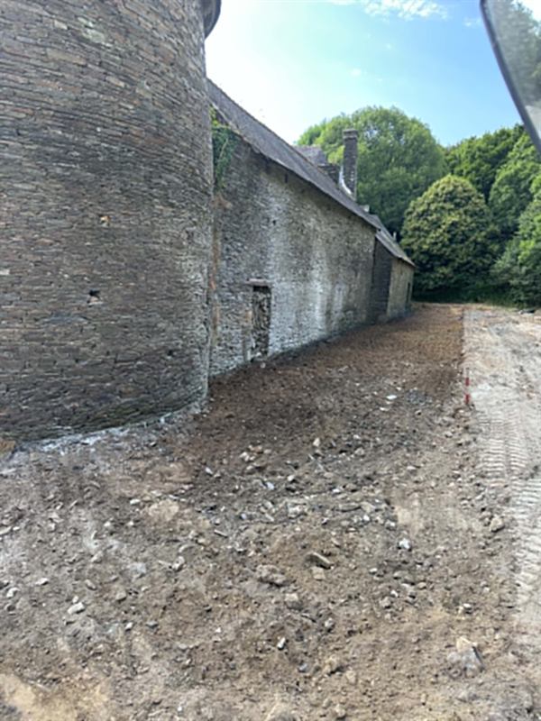 Cour terrassée le long d'un long bâtiment agricole en pierre