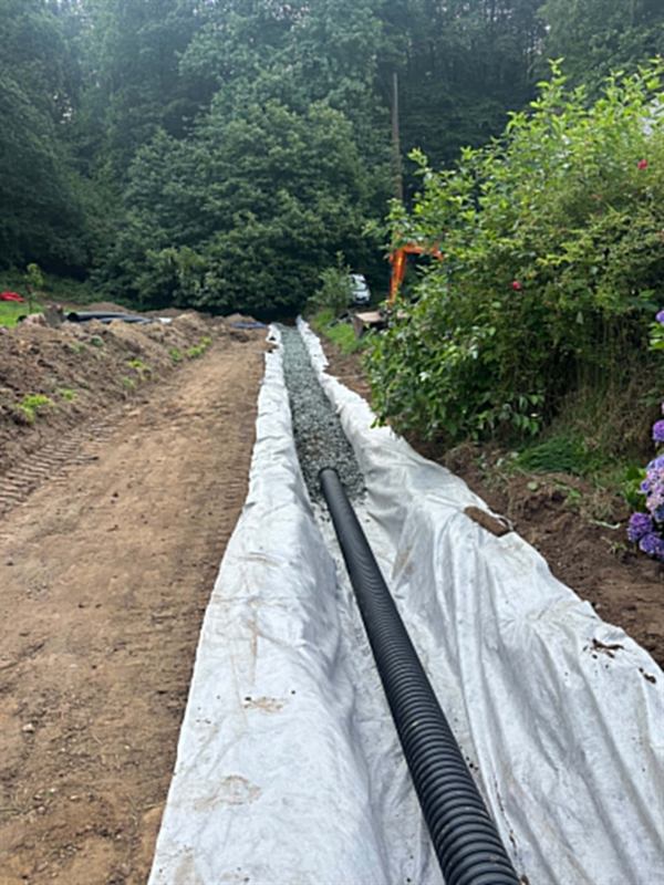 Tranchée drainante en cours de fermeture, drain et gravier sous géotextile