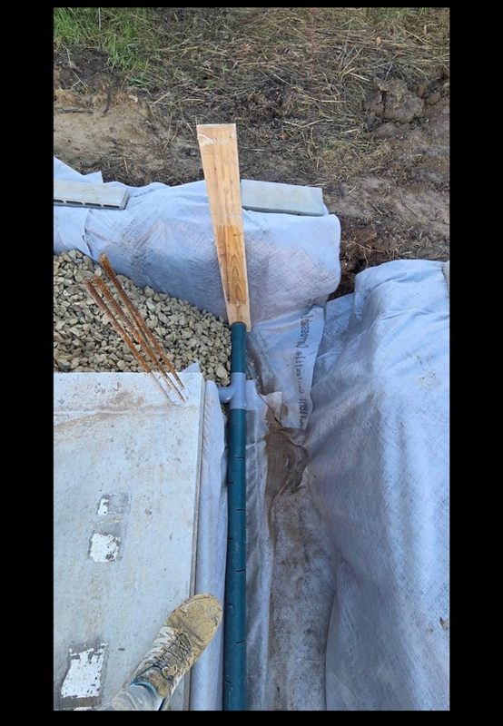 Canalisation posée dans une tranchée doublée de géotextile, gravier et regard béton