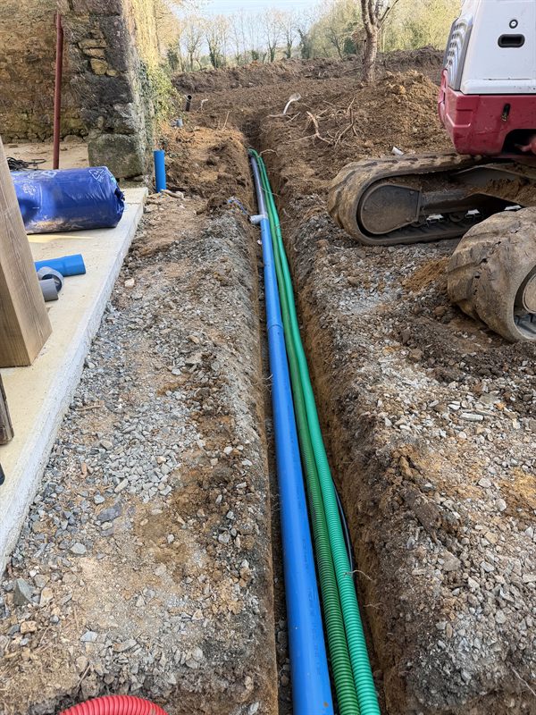 Tranchée de réseaux le long d'une plateforme : conduite d'eau bleue et gaines, pelle en bordure