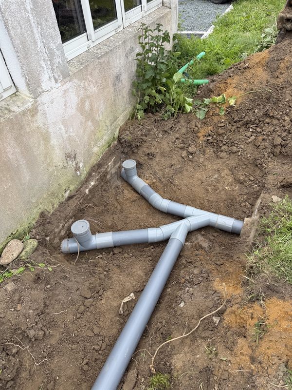 Raccordement de canalisations PVC et regards au pied d'une maison